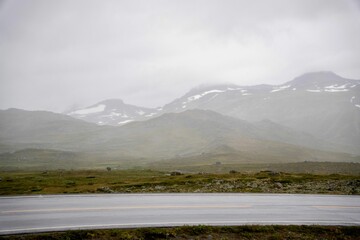 Highway against the backdrop of snow-capped mountains hidden in fog