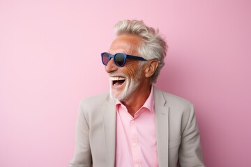 Portrait of a cheerful man in his 70s laughing while standing against solid pastel color wall