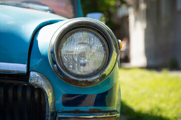 Old round headlight close up view  . front light details blue car