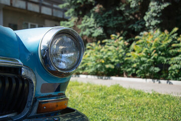 Old round headlight close up view . Copy space . front light details blue car