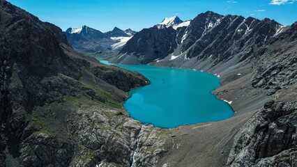 Turquoise Ala-Kol mountain lake surrounded by snowcapped mountains in Kyrgyzstan.