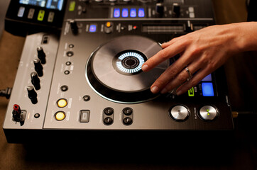 Close up portrait of female disc jockey hand mixing tracks on professional sound mixer, playing...