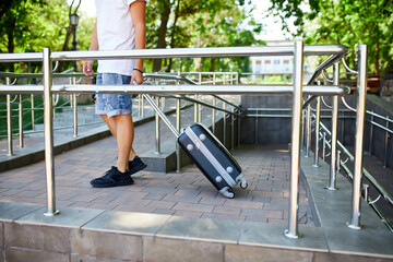 Man Walking With Wheeled Suitcase Down Ramp at Daytime