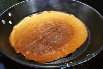 Pancake Cooking in Black Non-Stick Frying Pan: Breakfast Preparation Concept for Kitchen, Culinary Arts, and Food Photography