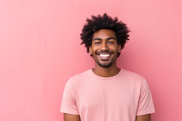 Fototapeta premium Portrait of a happy afro-american man in his 20s smiling at the camera in front of solid pastel color wall