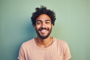 Fototapeta premium Portrait of a cheerful indian man in his 20s smiling at the camera in solid pastel color wall