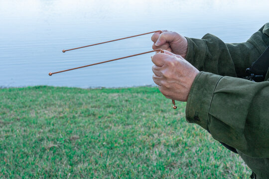Person using dowsing rods to discover the source of water