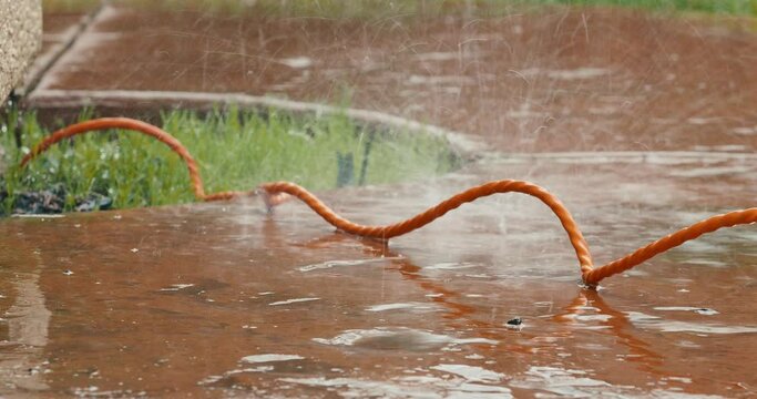 Closeup of heavy rain over an orange extension cord outdoors