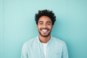 Fototapeta premium Portrait of a smiling indian man in his 20s smiling at the camera isolated in solid pastel color wall