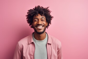 Fototapeta premium Portrait of a smiling afro-american man in his 20s smiling at the camera on solid pastel color wall