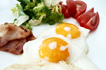 Delicious Breakfast Plate with Sunny Side Up Eggs, Crispy Bacon, Fresh Tomatoes, and Green Salad - Perfect for Brunch Menu Design or Healthy Eating Promotion