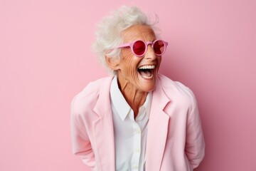 Portrait of a joyful elderly woman in her 90s laughing over solid pastel color wall
