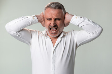 Man in white shirt with hands covering ears in worried gesture