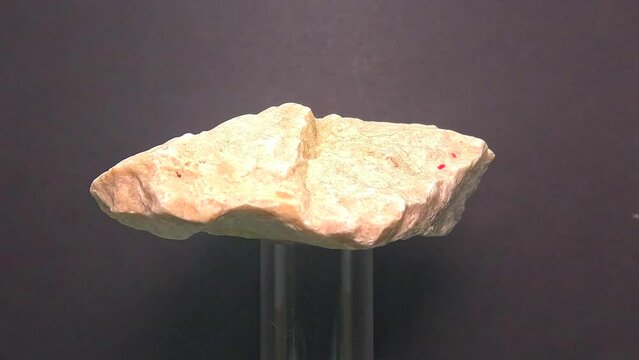 Closeup shot of a granite stone on a glass pole slowly rotating on a blur gray background