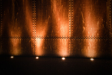 Rusted industrial metal wall illuminated by bright lamps