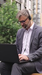 Busy adult man talking online while using headset outdoors.