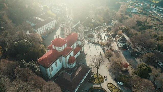 Aerial footage of Bom Jesus do Monte Basilica surrounded by autumn trees on a sunny day in Braga