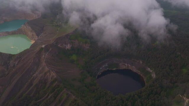 Aerial view of misty Kelimutu Volcano crater lake with green and blue scenery, Flores, Indonesia.