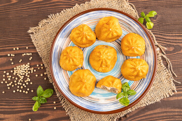 Manti dumplings with pepper, basil on brown wooden. Top view