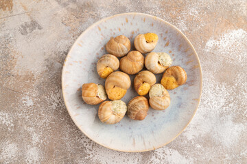 Grape (Burgundy) snails with butter and cheese on brown concrete, top view