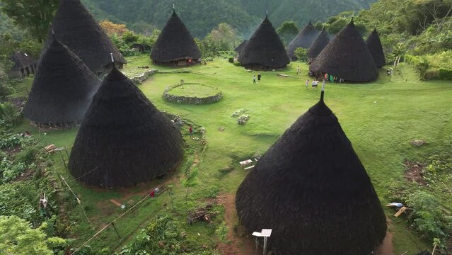 Aerial view of traditional village with thatched roof huts nestled in lush mountain nature, Wae Rebo, Flores, Indonesia.