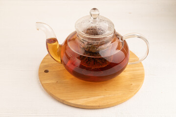 Red tea with herbs in glass teapot on white wooden. Top view.