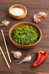 Chuka seaweed salad in wooden bowl on brown wooden. Side view