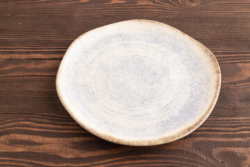 Empty blue and white ceramic plate on brown wooden. Side view, copy space