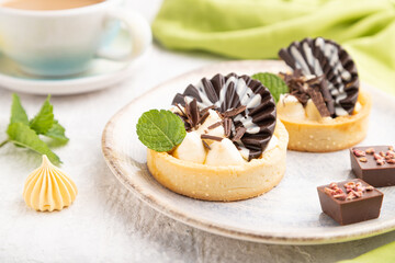 Sweet tartlets with chocolate and cheese cream with cup of coffee on a gray concrete background. side view, selective focus.