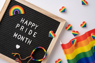 Letter board with 'Happy Pride Month' message surrounded by rainbow hearts, flag, and bracelet...
