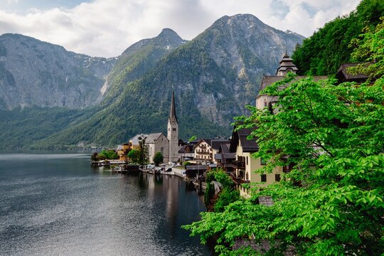 the water is reflecting the mountainside and houses in the background