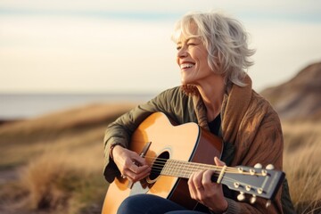 Portrait of a grinning woman in her 50s playing the guitar while standing against...