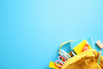 Back to School Essentials. School supplies spilling from a vibrant yellow bag on blue background. Perfect for educational themes, stationery marketing, and academic promotions