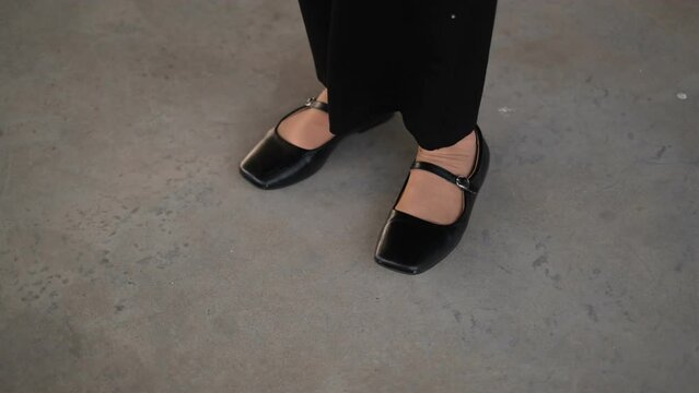 woman in black shoes  nervously taps her feet close-up of her feet