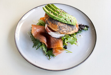 Delicious bagel filled with salted salmon, arugula, avocado and goat cheese .