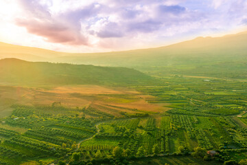 scenic rustic landscape with green hills and farms in a mountain valley during colorful cloudy...