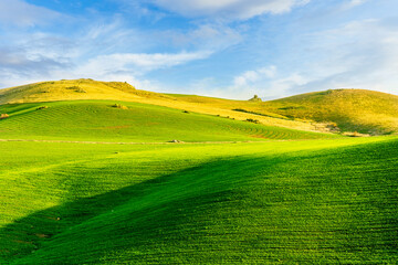 scenery rural view of a contryside farm in green fields and hills with amazing cloudy sky on background