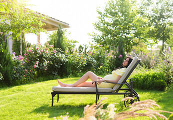 Pregnant woman relaxing and enjoying life in nature. Happy pregnancy. Woman relaxing on sun lounger...