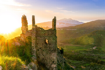 immersive landscape of old castle ruins on foreground and beautiful mountains with sunset with...