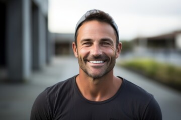 Fototapeta premium Portrait of a grinning man in his 40s smiling at the camera isolated in bare concrete or plaster wall