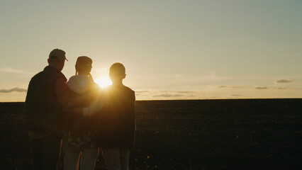 A family of farmers admires the sunset in their own field