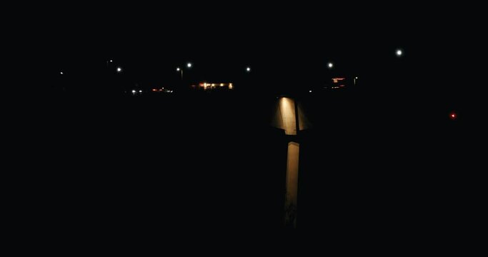 Night view of vehicles and cars driving on a bridge with a light pole lighting a concrete pile