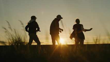The setting sun illuminates a field where a family of farmers dances joyfully.
