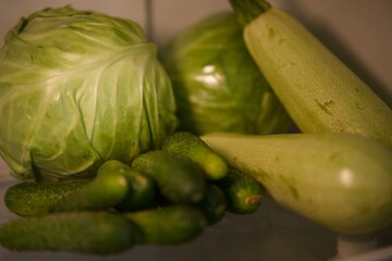 Green vegetables are in the refrigerator.
Zucchini, cabbage, cucumbers lie on a shelf in the refrigerator