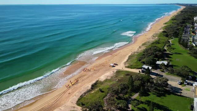 Drone footage of Kawana Beach and people walking in a coastal parking lot in Buddina, Australia