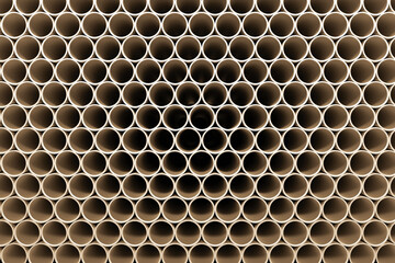 A large stack of new pipes lies on a construction site.