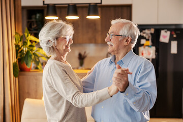 Romantic senior couple is dancing and having fun at home.