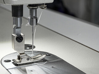 Close-up of a part of a sewing machine with a needle in which thread is threaded, for sewing...