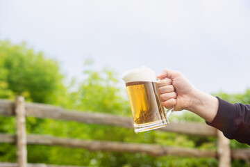 The hand of a man shows a glass of beer .