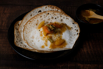 Aappam with Sambar on a wooden table. Appam or Palappam is one of the most popular and traditional breakfast in Kerala and South India.